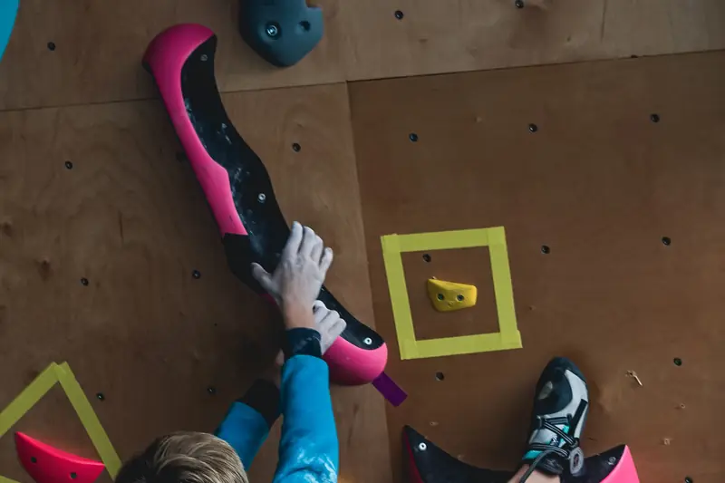 Ein kleiner Junge klettert an einer bunten Kletterwand