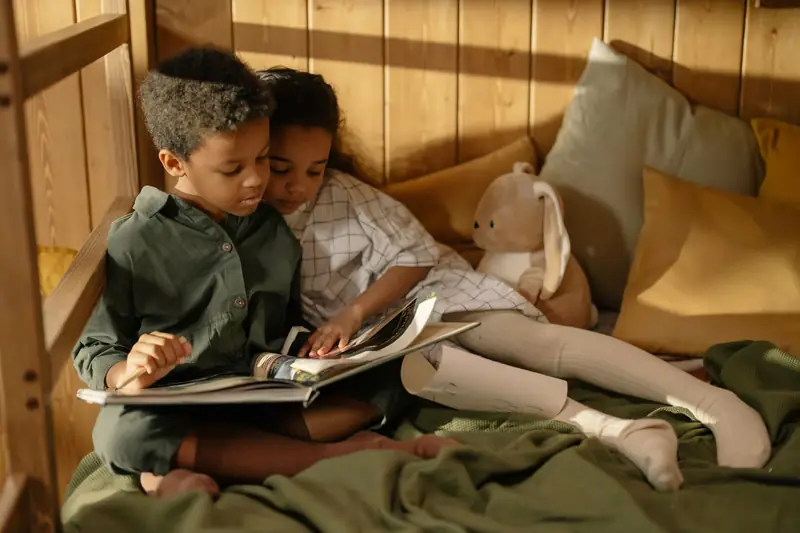 Zwei kleine Kinder lesen eng aneinander gekuschelt ein Märchenbuch