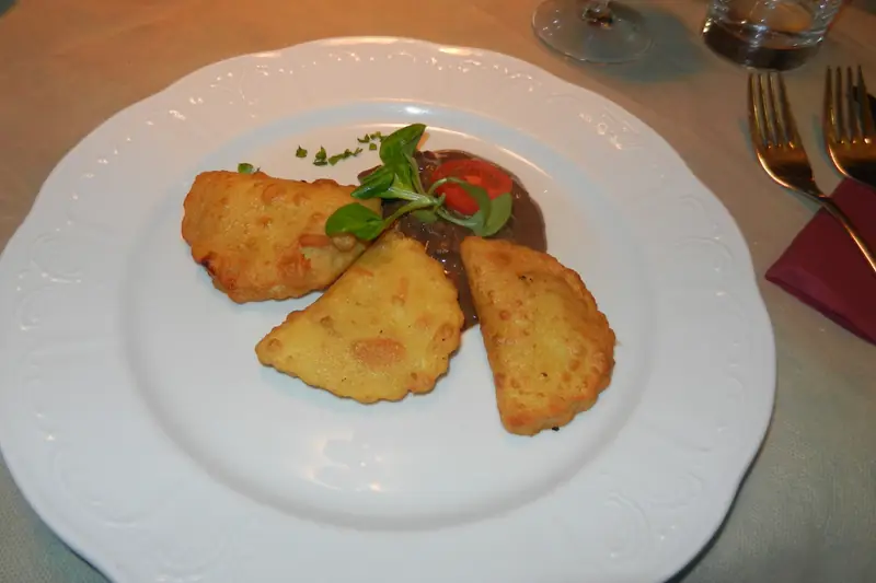 Golden fried Krapfen pastries on a white plate at a Törggelen table
